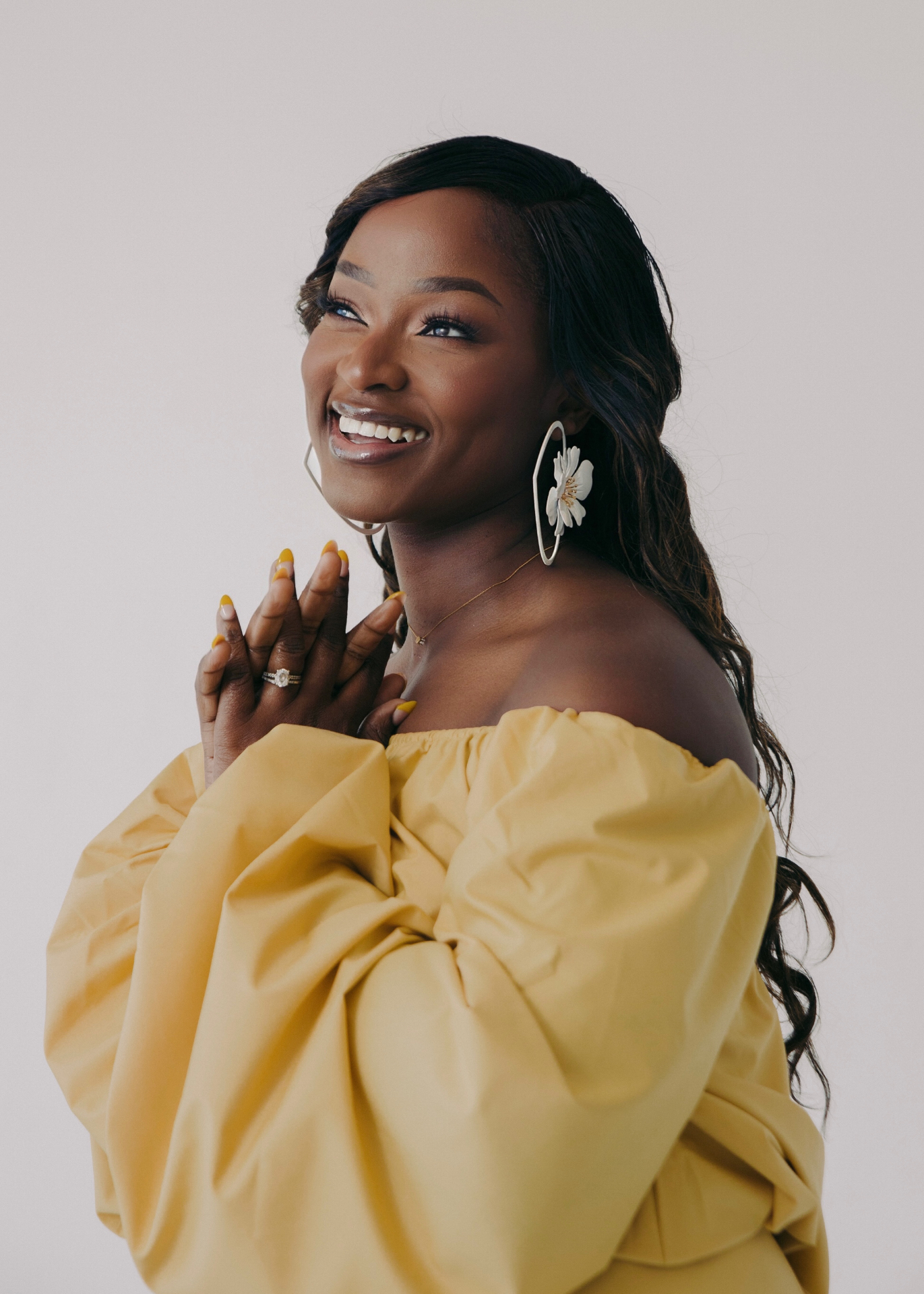Ejiro Obayomi in a flowing yellow dress, smiling upward